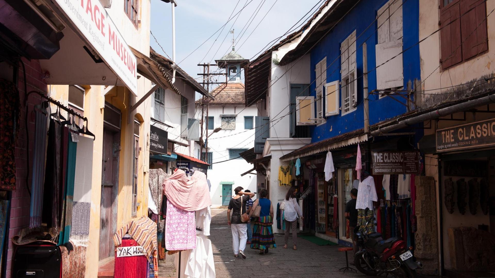 Passanten gehen in Kochi in Südindien vor der Paradesi-Synagoge eine Straße entlang.