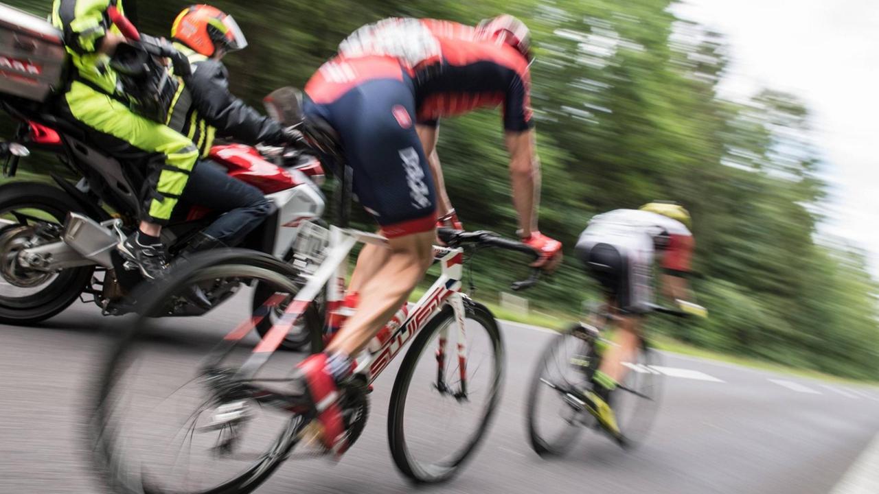 Zwei Radrennfahrer verschwommen von hinten fotografiert, im Hintergrund ein Versorgungsmotorrad. Zwei Radrennfahrer verschwommen von hinten fotografiert, im Hintergrund ein Versorgungsmotorrad.