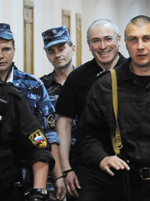 Michail Chodorkowski geht umringt von Aufsichtspersonal einen Gang im Gefängnis entlang.