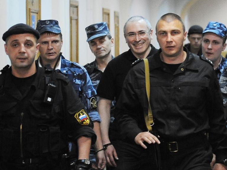 Michail Chodorkowski geht umringt von Aufsichtspersonal einen Gang im Gefängnis entlang.