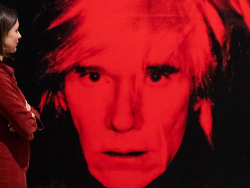 Eine Mitarbeiterin der Tate Modern Gallery betrachtet das Werk "Self Portrait" von Andy Warhol.