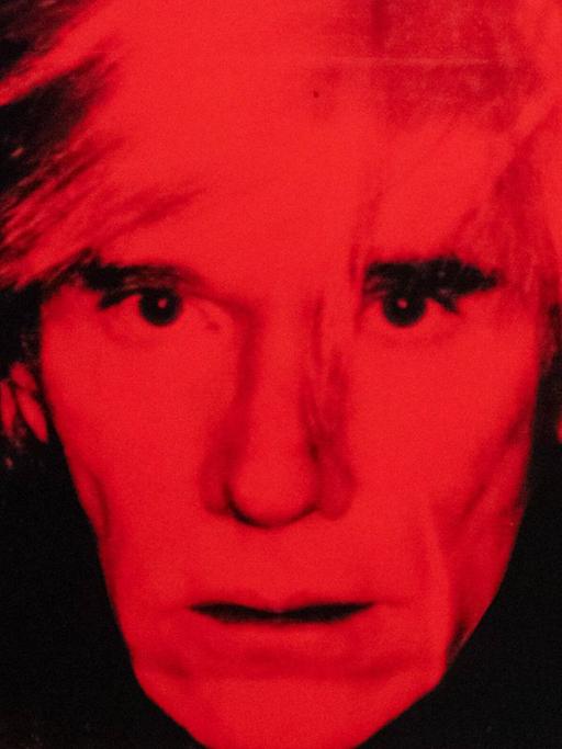 Eine Mitarbeiterin der Tate Modern Gallery betrachtet das Werk "Self Portrait" von Andy Warhol.