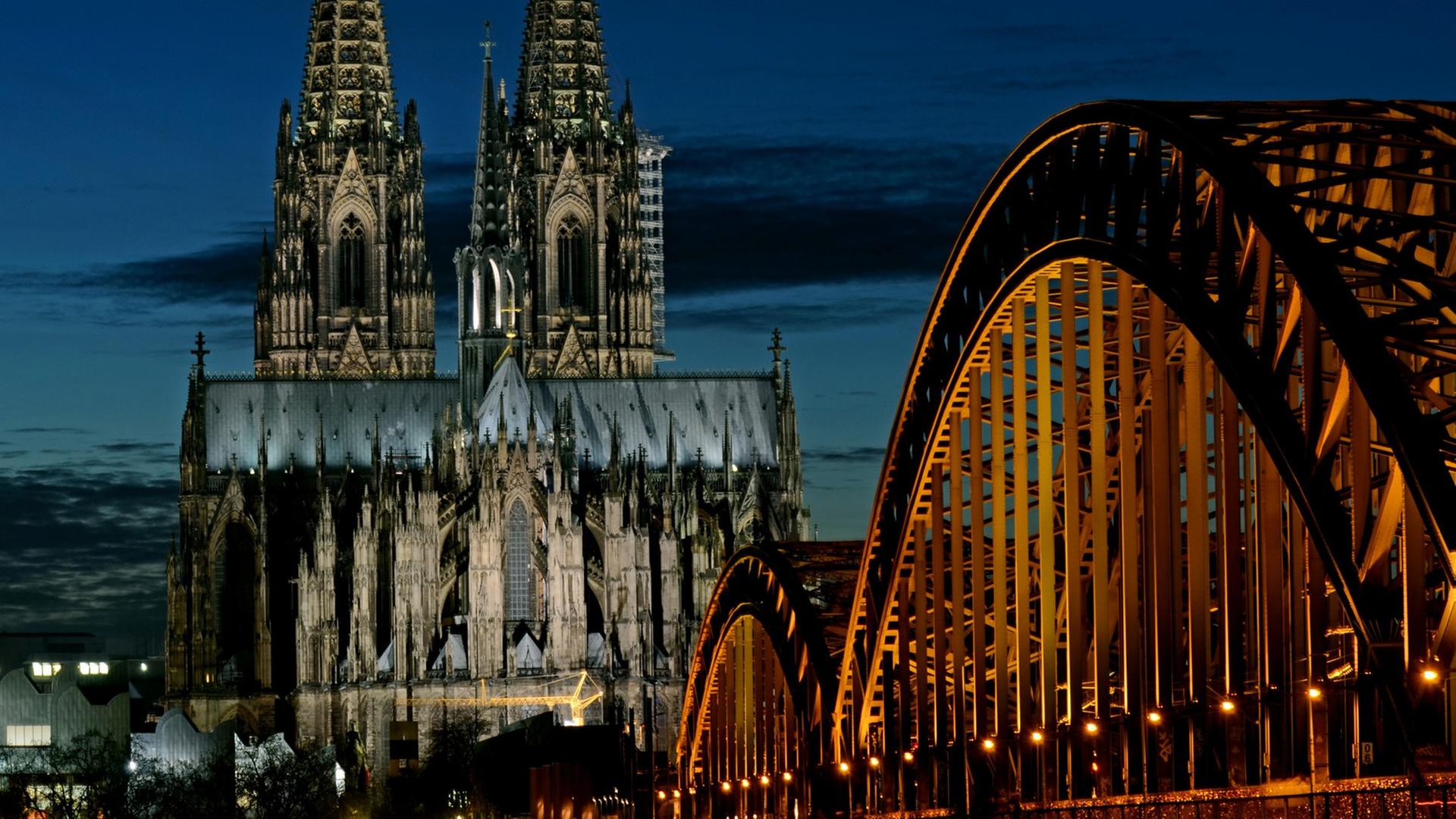 Der angestrahlte Kölner Dom, davor die Hohenzollernbrücke in Köln. Der angestrahlte Kölner Dom, davor die Hohenzollernbrücke in Köln.