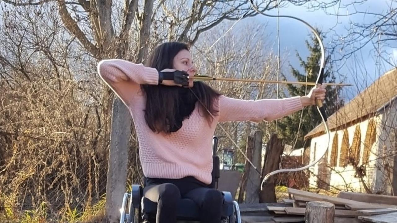 Eine junge Frau im Rollstuhl mit Pfeil und Bogen. Eine junge Frau im Rollstuhl mit Pfeil und Bogen.