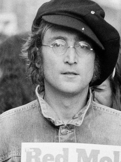 Schwarzweiß Fotografie von John Lennon im Hyde Park. Neben ihm steht Yoko Ono, im Hintergrund stehen weitere junge Menschen.