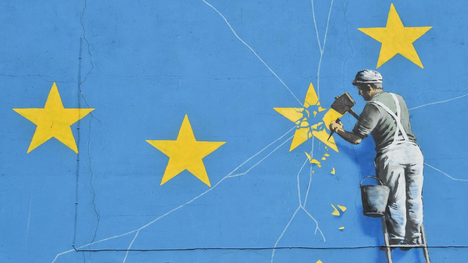 Ein Wandbild von Banksy in der britischen Hafenstadt Dover zeigt eine riesige EU-Flagge und einen Arbeiter, der einen Stern aus der Flagge heraus meißelt. Ein Wandbild von Banksy in der britischen Hafenstadt Dover zeigt eine riesige EU-Flagge und einen Arbeiter, der einen Stern aus der Flagge heraus meißelt.