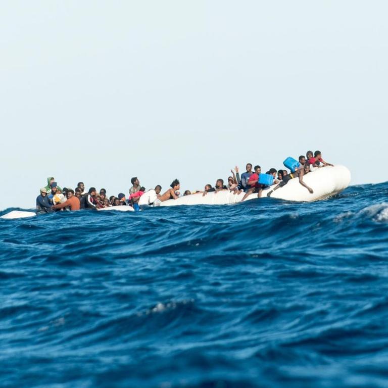 Migranten, die von Libyen aus nach Italien wollen, sitzen auf einem Schlauchboot im Mittelmeer. Sie warten am 27.01.2018 vor der libyschen Küste auf den Rettungseinsatz von SOS Mediterranee und der italienischen Küstenwache.