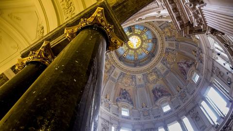 Blick entland einer Säule nach ob in die reich verziehrte Kuppel des Berliner Doms.
