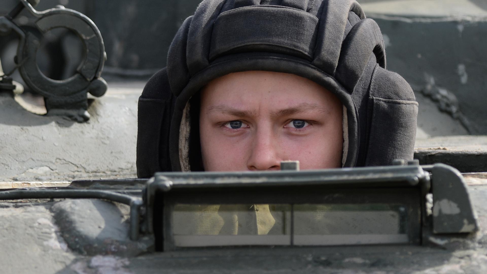 Ein russischer Soldat schaut aus einem Panzerfahrzeug Ein russischer Soldat schaut aus einem Panzerfahrzeug