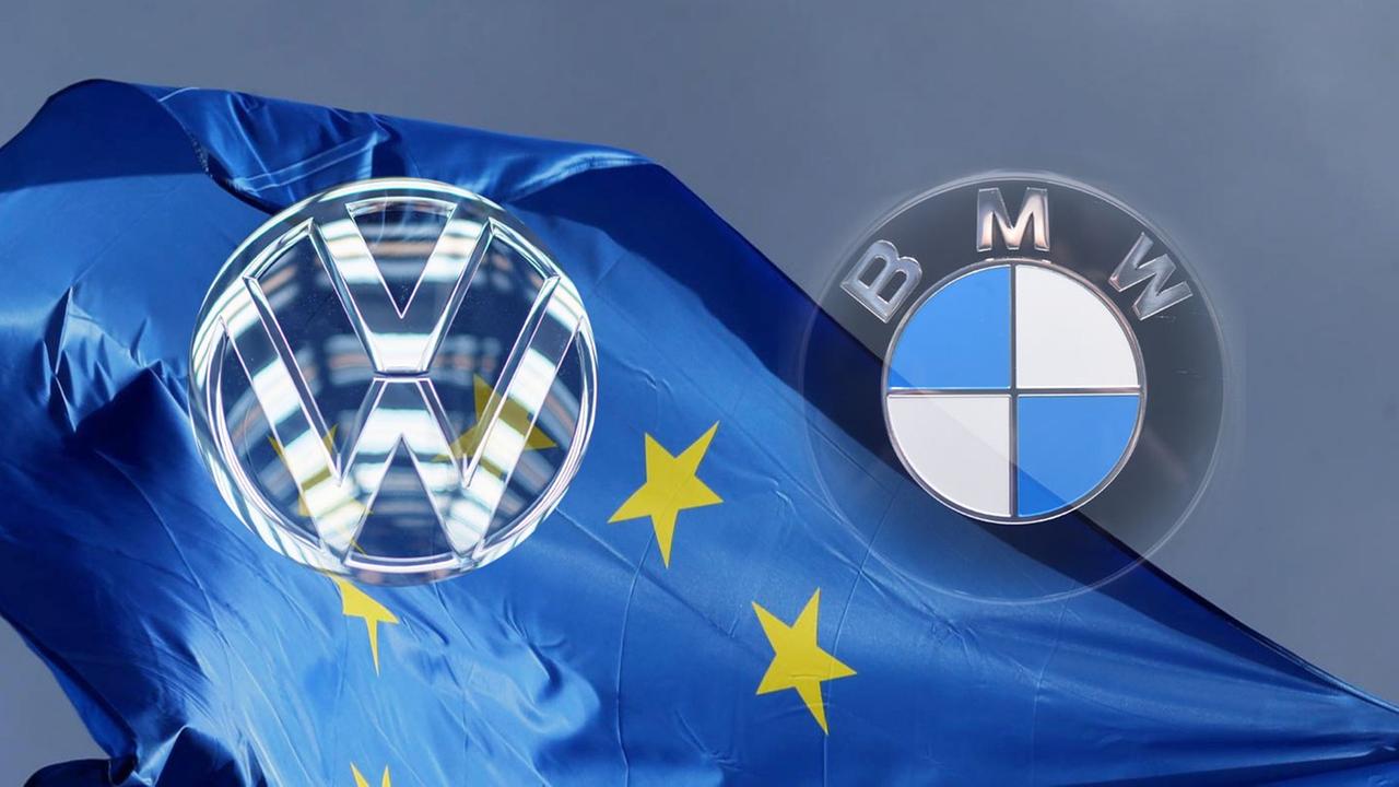 Die Logos von VW und BMW vor einer Flagge von der EU. Die Logos von VW und BMW vor einer Flagge von der EU.