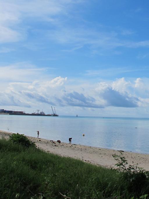 Ein Strand, blauer Himmel und im Hintergrund etwas Industrie.