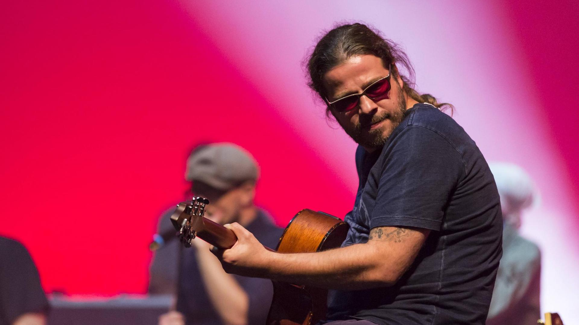 Gitarrist Andreas Bayless von der deutschen Band Söhne Mannheims live beim Blue Balls Festival im Konzertsaal des KKL Luzern, Schweiz. Der Musiker trägt eine Sonnenbrille und hat die Haare zum Zopf zusammengebunden. Gitarrist Andreas Bayless von der deutschen Band Söhne Mannheims live beim Blue Balls Festival im Konzertsaal des KKL Luzern, Schweiz. Der Musiker trägt eine Sonnenbrille und hat die Haare zum Zopf zusammengebunden.
