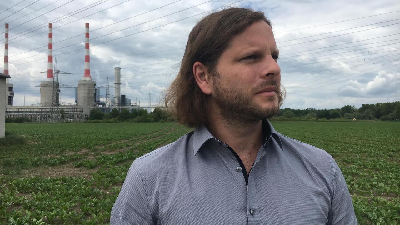 Porträtaufnahme von Matthias Kolbe, im Hintergrund ein Acker und das Gaskraftwerk Irsching Porträtaufnahme von Matthias Kolbe, im Hintergrund ein Acker und das Gaskraftwerk Irsching