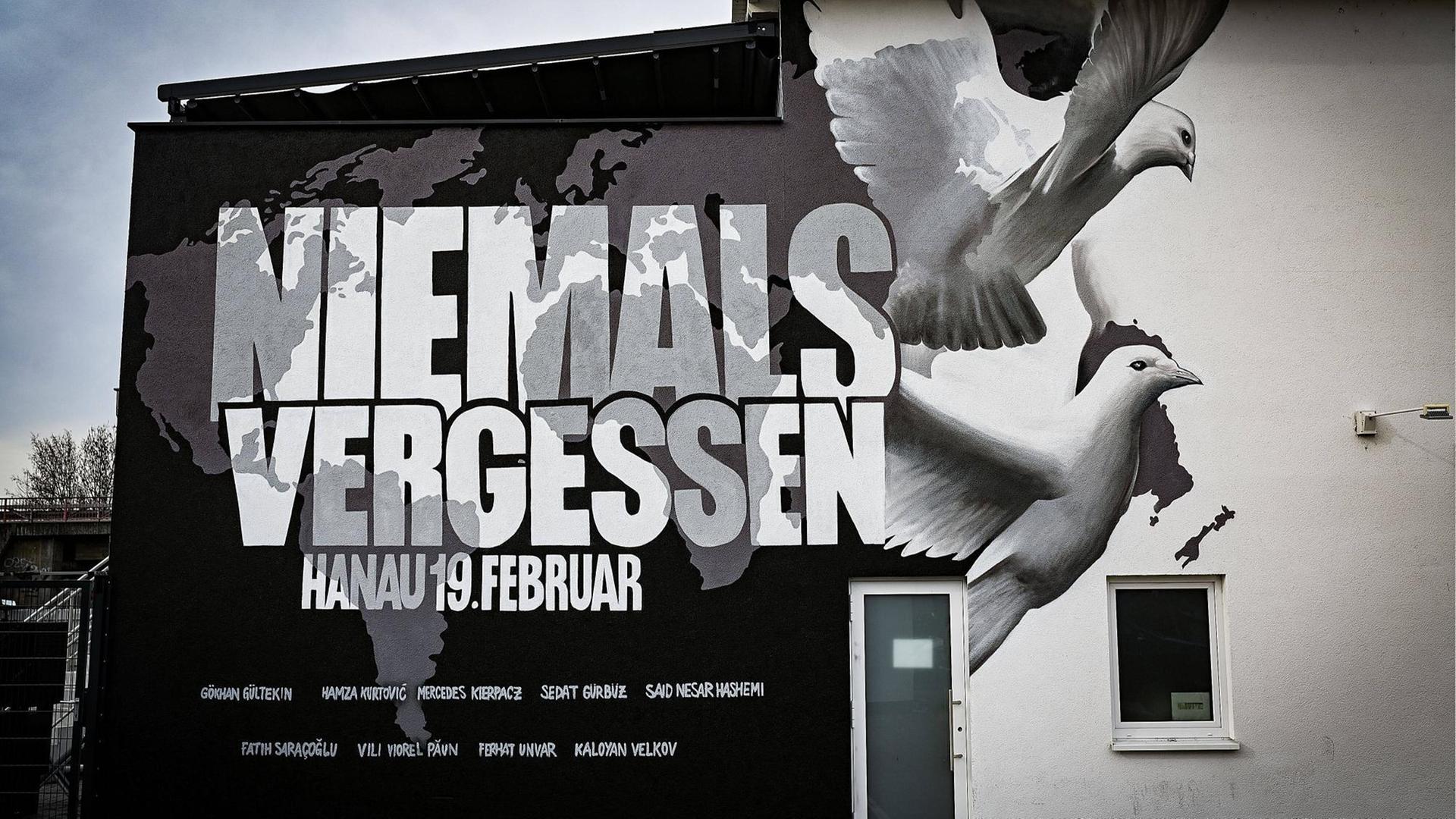 Ein Graffiti an einer Hauswand in Hanau zeigt eine Weltkarte, die Namen von neun der zehn Ermordeten, zwei weiße Tauben und die Worte: Niemals vergessen, Hanau 19. Februar Ein Graffiti an einer Hauswand in Hanau zeigt eine Weltkarte, die Namen von neun der zehn Ermordeten, zwei weiße Tauben und die Worte: Niemals vergessen, Hanau 19. Februar