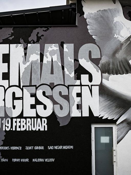 Ein Graffiti an einer Hauswand in Hanau zeigt eine Weltkarte, die Namen von neun der zehn Ermordeten, zwei weiße Tauben und die Worte: Niemals vergessen, Hanau 19. Februar
