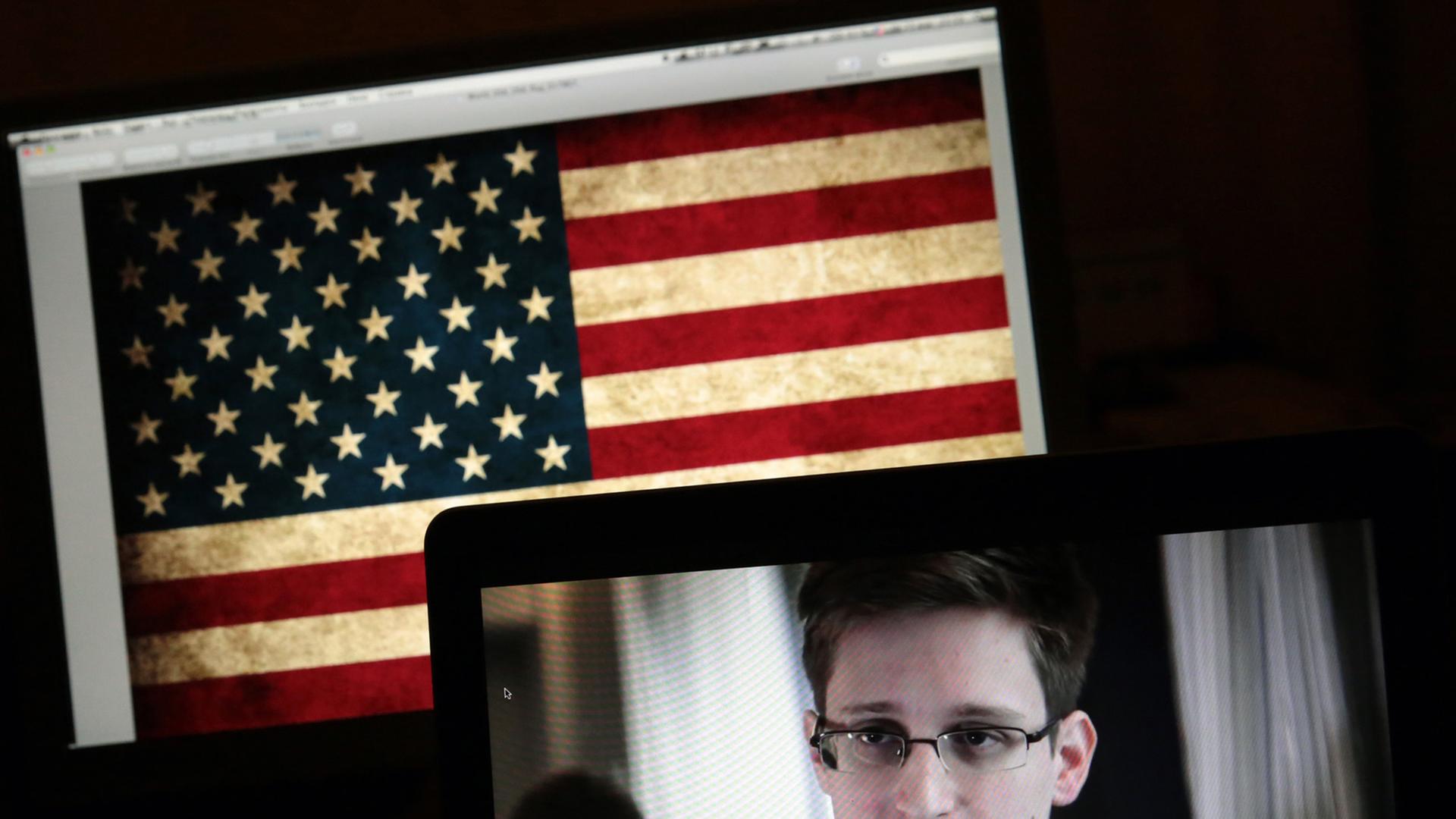 Edward Snowden auf einem Bildschirm vor einer US-Flagge