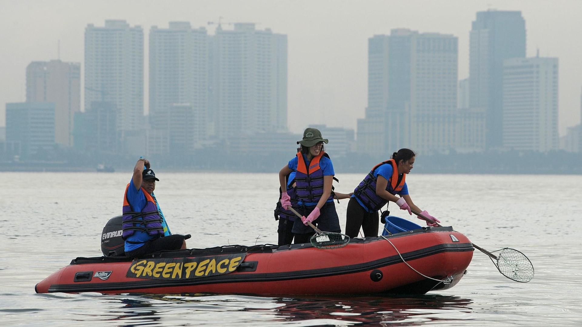 Greenpeace-Aktivisten auf einem Schlauchboot, im Hintergrund Hochhäuser von Manila. Greenpeace-Aktivisten auf einem Schlauchboot, im Hintergrund Hochhäuser von Manila.