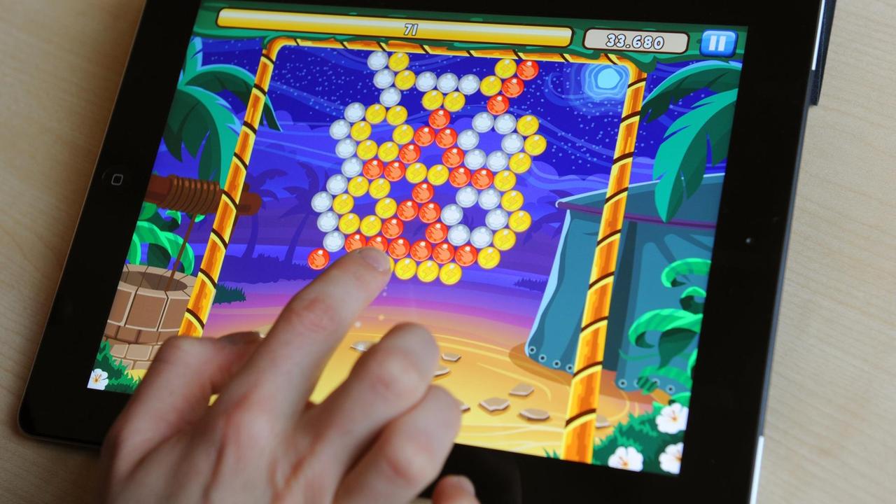 Eine Hand bedient das Geschicklichkeitsspiel "Bubble Island" auf einem Tablet.
