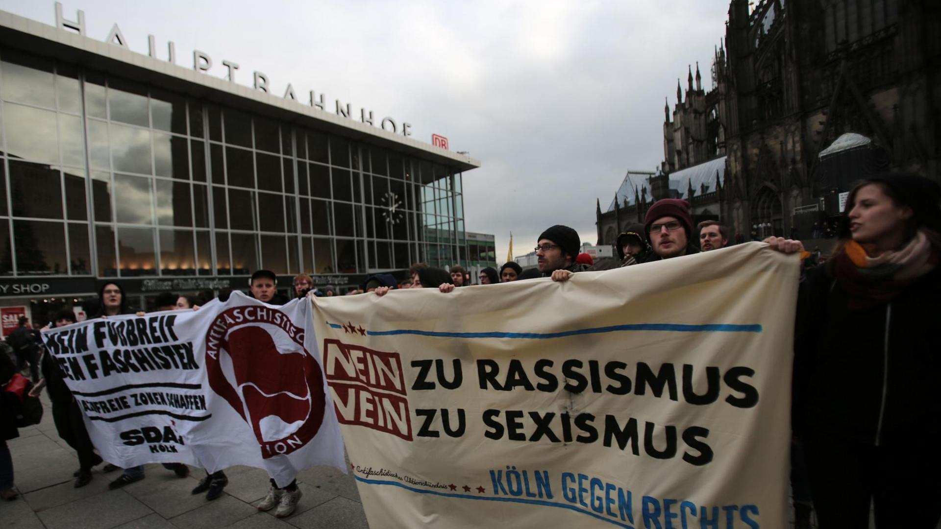 Demonstranten mit Transparenten vor dem Hauptbahnhof, darauf zu lesen "Nein zu Rassismus, nein zu Sexismus". Demonstranten mit Transparenten vor dem Hauptbahnhof, darauf zu lesen "Nein zu Rassismus, nein zu Sexismus".