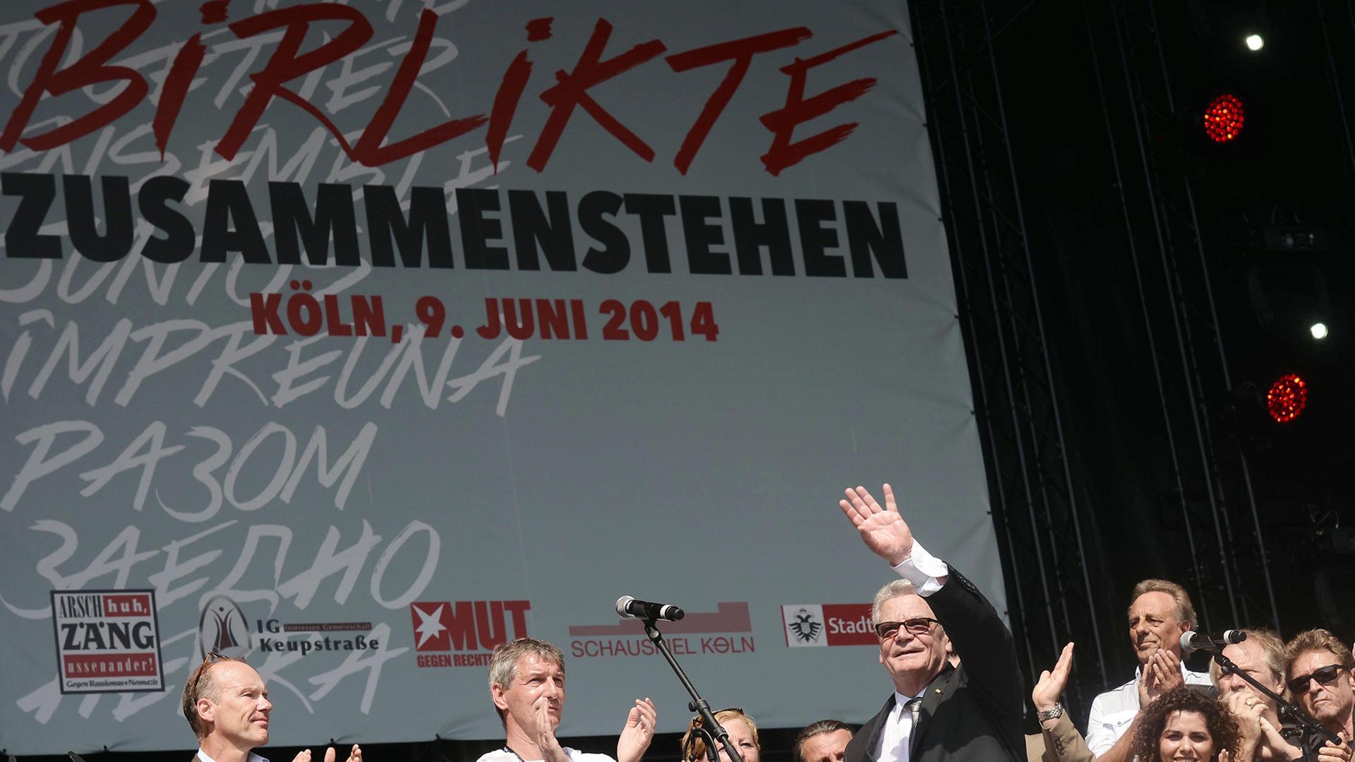 Bundespräsident Joachim Gauck (M) steht zusammen mit dem Mitgliedern der "Arsch Huh AG" am 09.06.2014 beim Kulturfest "Birlikte - Zusammenstehen" zum Gedenken an den NSU-Anschlag in Köln vor zehn Jahren (Nordrhein-Westfalen) auf der Bühne.