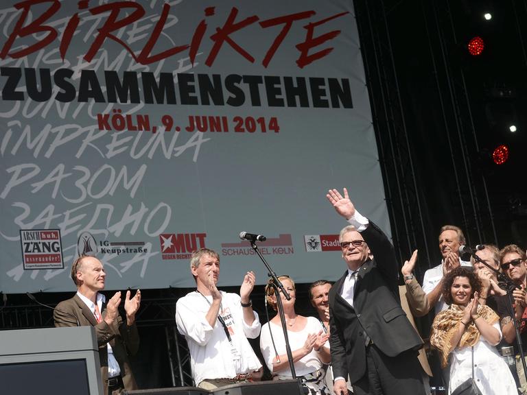 Bundespräsident Joachim Gauck (M) steht zusammen mit dem Mitgliedern der "Arsch Huh AG" am 09.06.2014 beim Kulturfest "Birlikte - Zusammenstehen" zum Gedenken an den NSU-Anschlag in Köln vor zehn Jahren (Nordrhein-Westfalen) auf der Bühne.