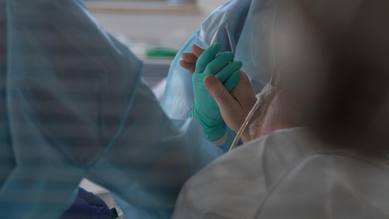 Eine Ärztin hält in der Intensivstation des Luisenhospitals die Hand eines Coronapatienten. In der Station werden zur Zeit acht Patienten mit Covid-19 behandelt.