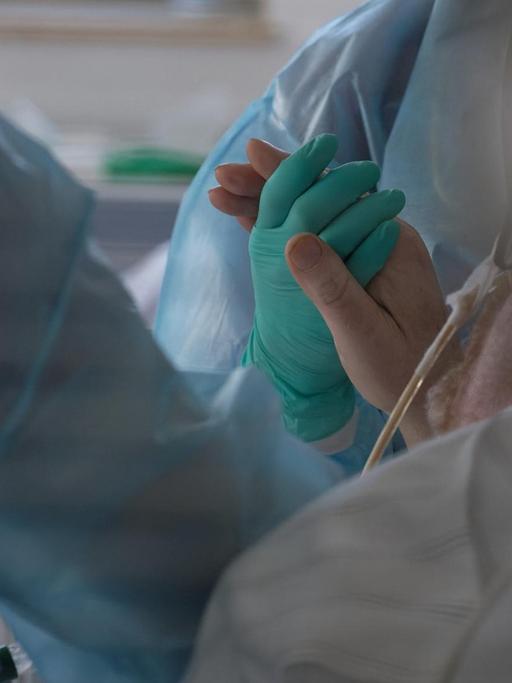Eine Ärztin hält in der Intensivstation des Luisenhospitals die Hand eines Coronapatienten. In der Station werden zur Zeit acht Patienten mit Covid-19 behandelt.
