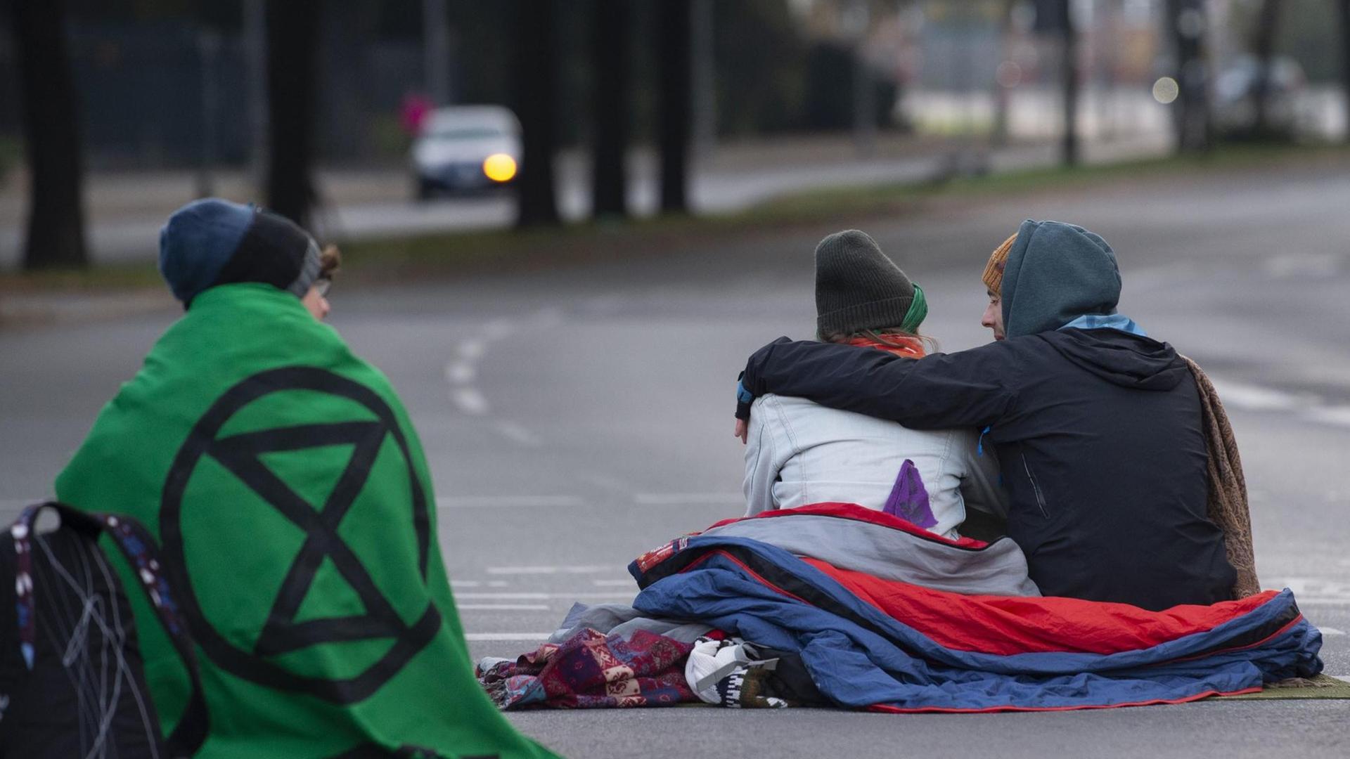 Aktivisten der Klimabewegung "Extinction Rebellion" blockieren sitzend eine Straße in Berlin.