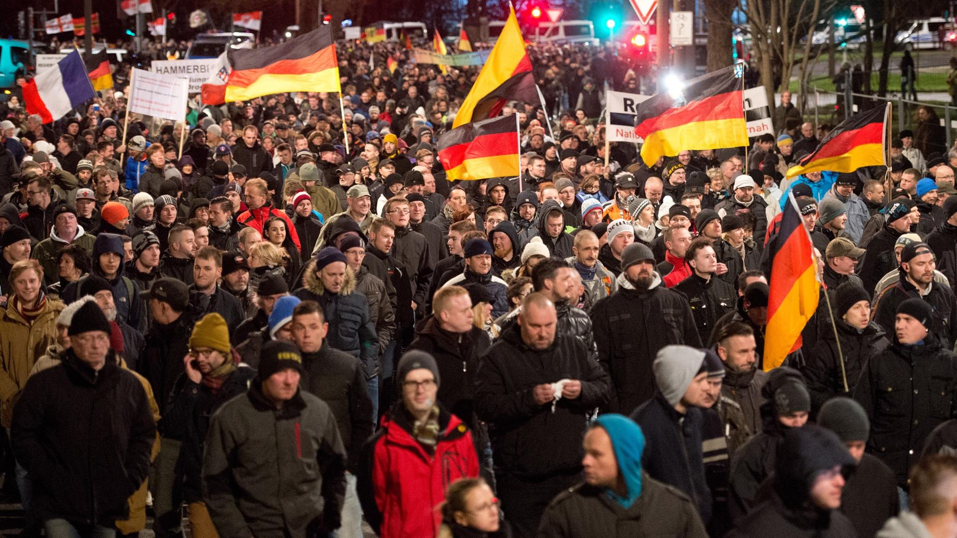 Eine Menschenmenge marschiert mit Deutschlandflaggen durch Dresden. Eine Menschenmenge marschiert mit Deutschlandflaggen durch Dresden.