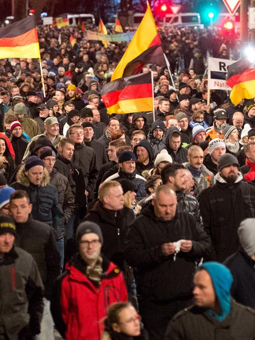 Eine Menschenmenge marschiert mit Deutschlandflaggen durch Dresden.