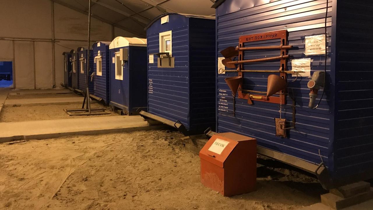 In einer Halle stehen nebeneinander blaue Container, die an Eisenbahnwaggons erinnern In einer Halle stehen nebeneinander blaue Container, die an Eisenbahnwaggons erinnern