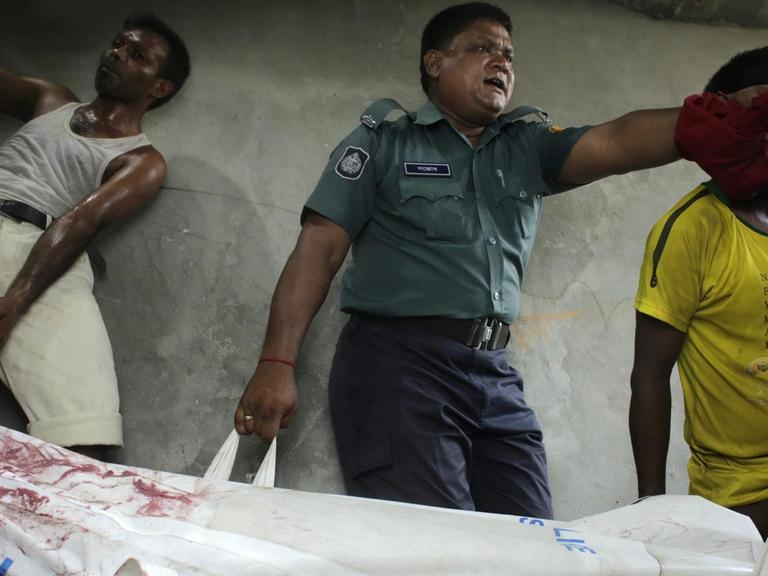 Sicherheitskräfte tragen den Leichnam des Bloggers Niloy Chakrabart eine Treppe hinunter (7.8). Nun wurden drei Verdächtige inhaftiert.