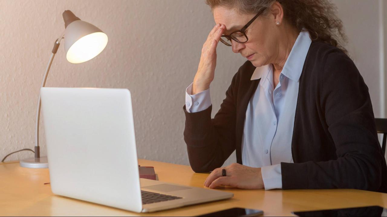 Besorgte Frau vor Laptop stützt ihren Kopf ab. Besorgte Frau vor Laptop stützt ihren Kopf ab.