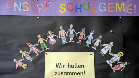 Gesehen in einer Grundschule: Auf einem schwarzen Brett steht "Wir halten zusammen!"