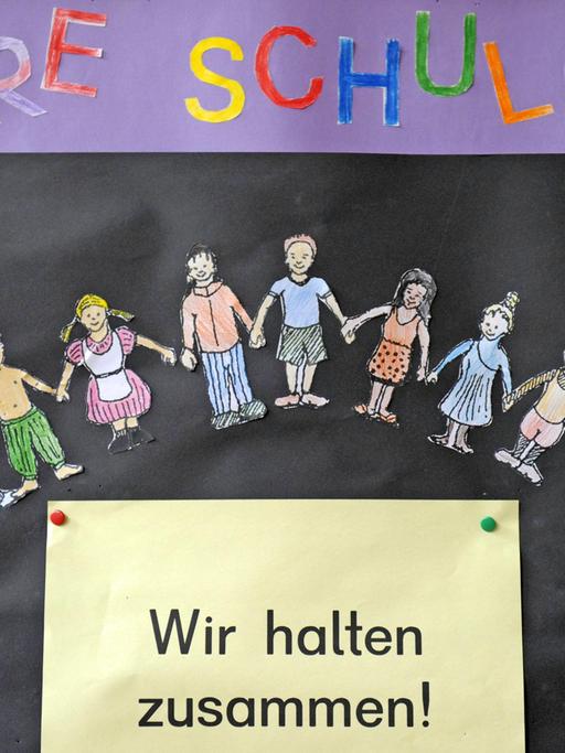 Gesehen in einer Grundschule: Auf einem schwarzen Brett steht "Wir halten zusammen!"