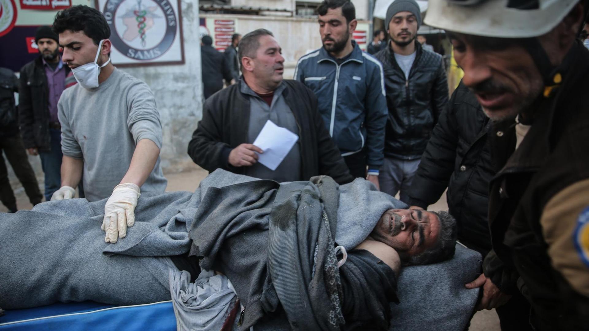 Männer tragen den Körper eines Luftangriff-Opfers auf einer Trage. In der Provinz Idlib wurde am 25. Februar 2020 von Flugzeugen der syrischen Streitkräfte ein mutmaßlicher Luftangriff auf eine Schule verübt.