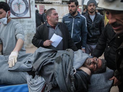 Männer tragen den Körper eines Luftangriff-Opfers auf einer Trage. In der Provinz Idlib wurde am 25. Februar 2020 von Flugzeugen der syrischen Streitkräfte ein mutmaßlicher Luftangriff auf eine Schule verübt.