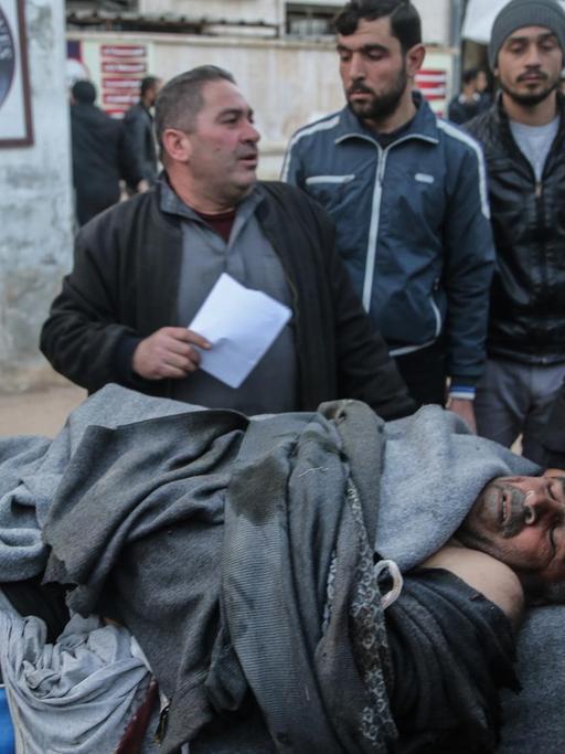 Männer tragen den Körper eines Luftangriff-Opfers auf einer Trage. In der Provinz Idlib wurde am 25. Februar 2020 von Flugzeugen der syrischen Streitkräfte ein mutmaßlicher Luftangriff auf eine Schule verübt.
