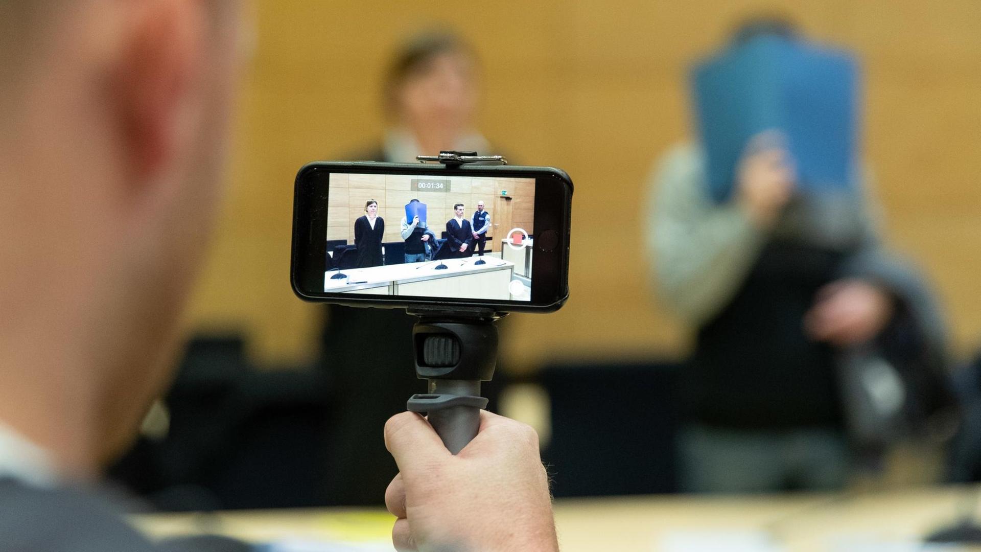Ein Journalist macht Filmaufnahmen mit seinem Smartphone im Gerichtssaal