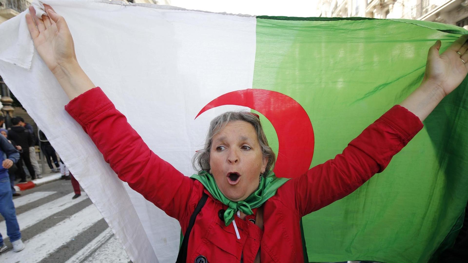 Eine Demonstrantin schwenkt während der Anti-Regierungs-Proteste eine algerische Flagge.