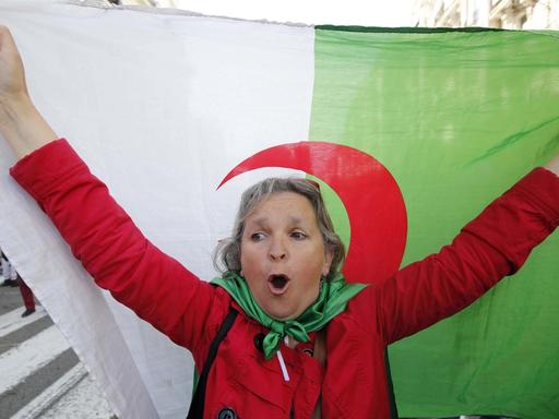 Eine Demonstrantin schwenkt während der Anti-Regierungs-Proteste eine algerische Flagge.