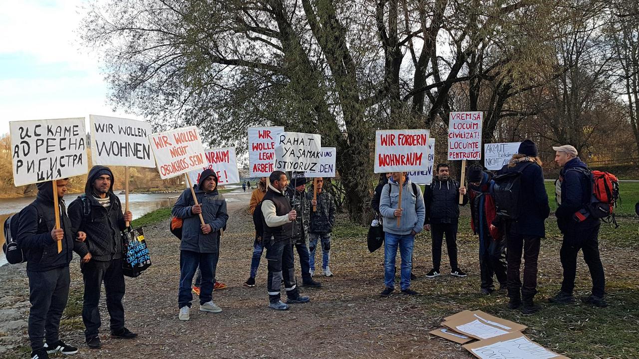 "Wir wollen wie Menschen wohnen", "Wir wollen nicht obdachlos sein", "Wir wollen legale Arbeit" – Obdachlose am Ufer der Isar in München halten Protestschilder in verschiedenen Sprachen hoch. "Wir wollen wie Menschen wohnen", "Wir wollen nicht obdachlos sein", "Wir wollen legale Arbeit" – Obdachlose am Ufer der Isar in München halten Protestschilder in verschiedenen Sprachen hoch.