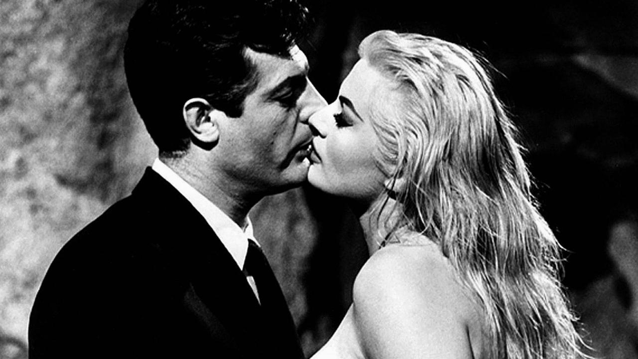 Großaufnahme in Schwarzweiß von Marcello Mastroianni und Anita Ekberg, die in einem Stadtbrunnen stehen und sich küssen. Großaufnahme in Schwarzweiß von Marcello Mastroianni und Anita Ekberg, die in einem Stadtbrunnen stehen und sich küssen.
