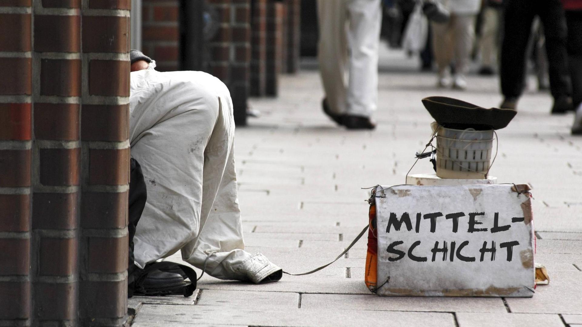 Um Spenden bittet ein Bettler in der Einkaufsstraße mit einem Schild Mittelschicht. (Bildmontage) Um Spenden bittet ein Bettler in der Einkaufsstraße mit einem Schild Mittelschicht. (Bildmontage)