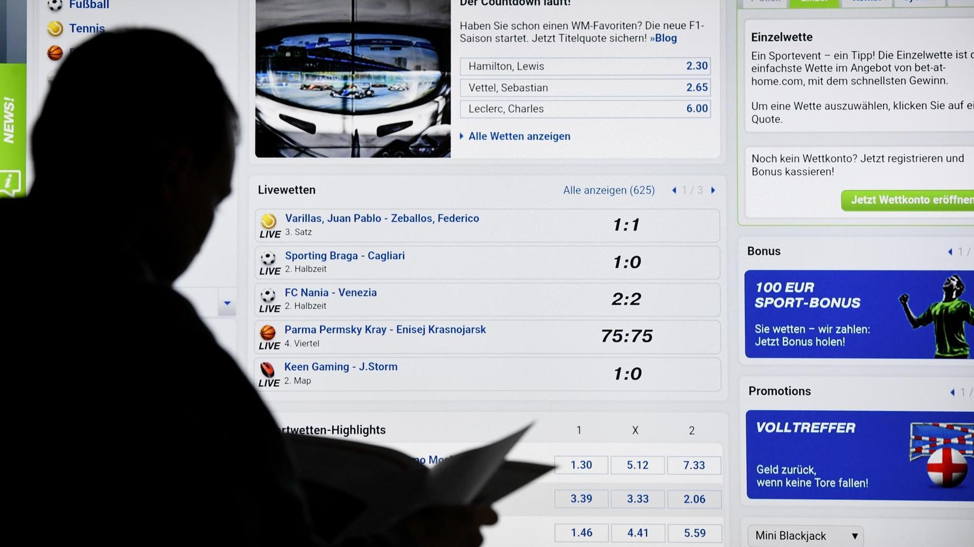 Ein Mann steht vor einem Bildschirm mit einer Seite eines Anbieters für Sport-Wetten. Ein Mann steht vor einem Bildschirm mit einer Seite eines Anbieters für Sport-Wetten.