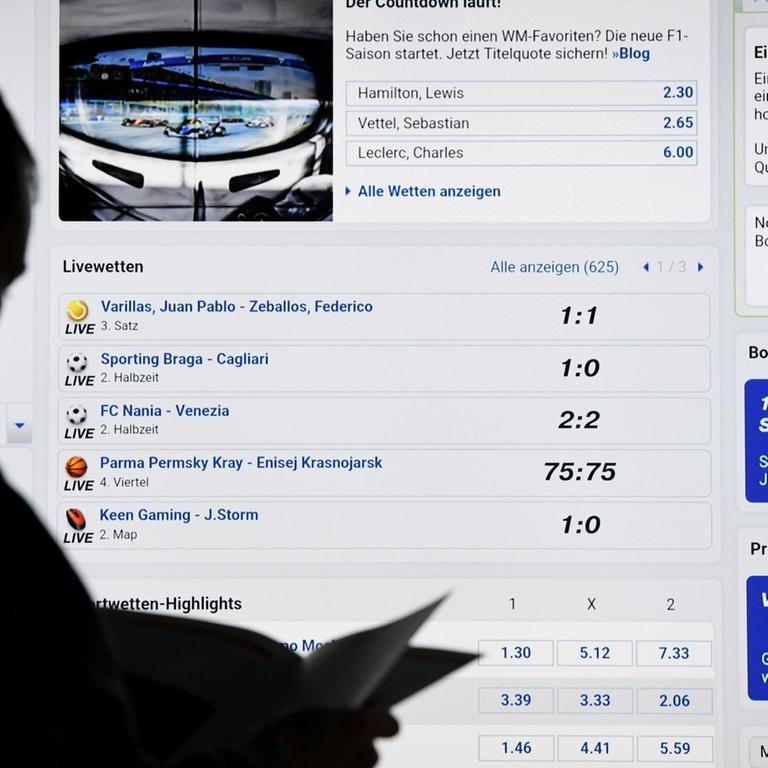 Ein Mann steht vor einem Bildschirm mit einer Seite eines Anbieters für Sport-Wetten.