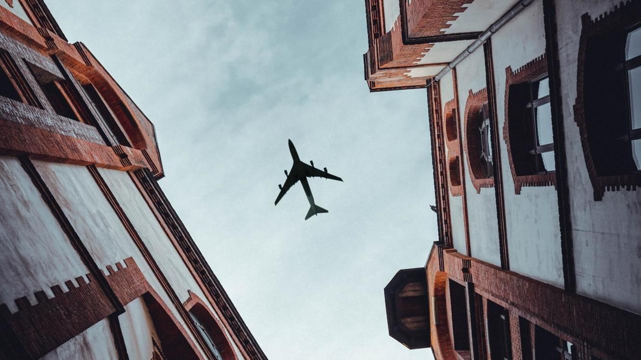 Ein Flugzeug am Himmel zwischen zwei engen Altbau-Fassaden. Ein Flugzeug am Himmel zwischen zwei engen Altbau-Fassaden.