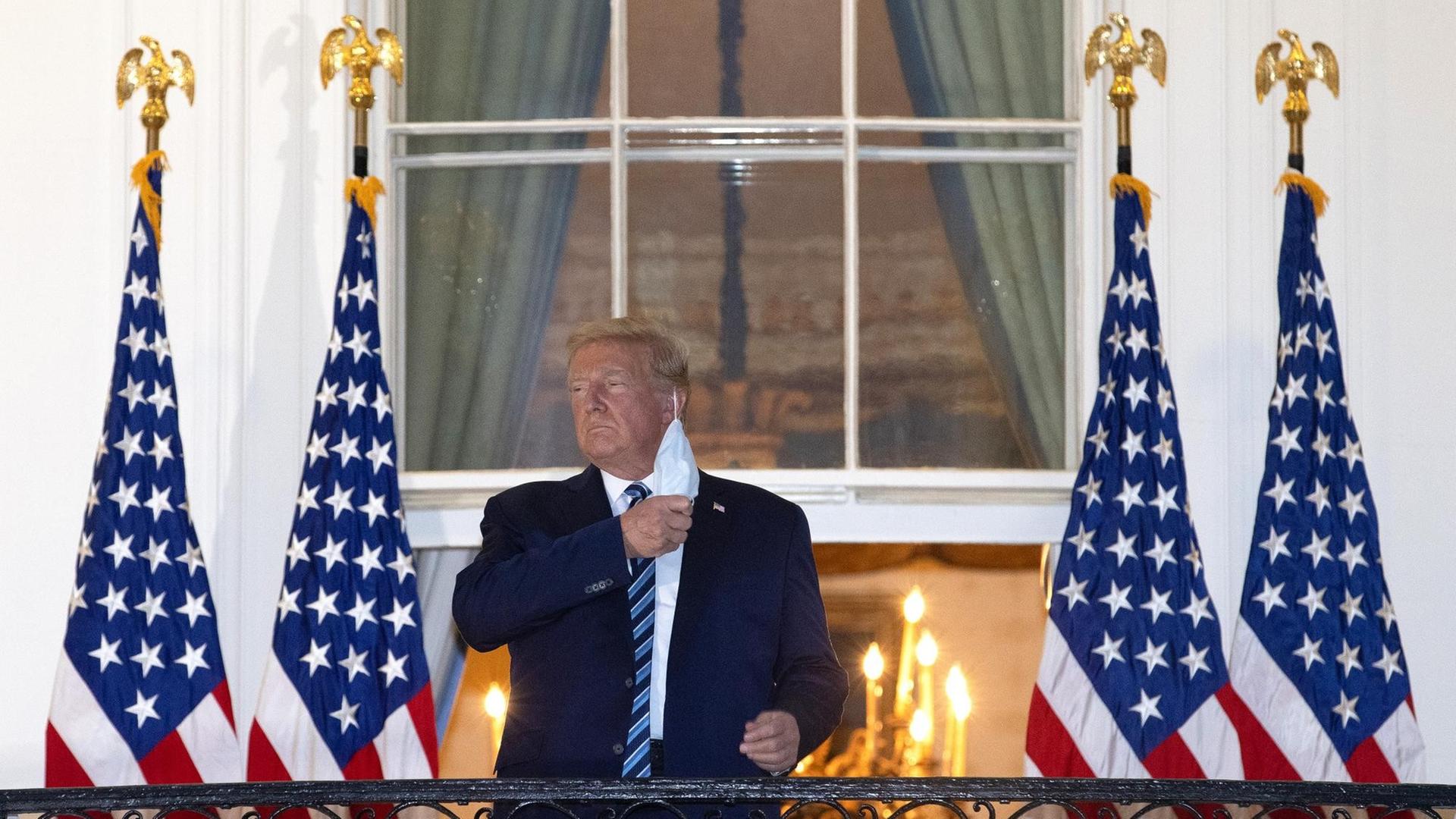 Präsident Trump steht auf dem Balkon am Weißen Haus und nimmt seine Schutzmaske ab Präsident Trump steht auf dem Balkon am Weißen Haus und nimmt seine Schutzmaske ab