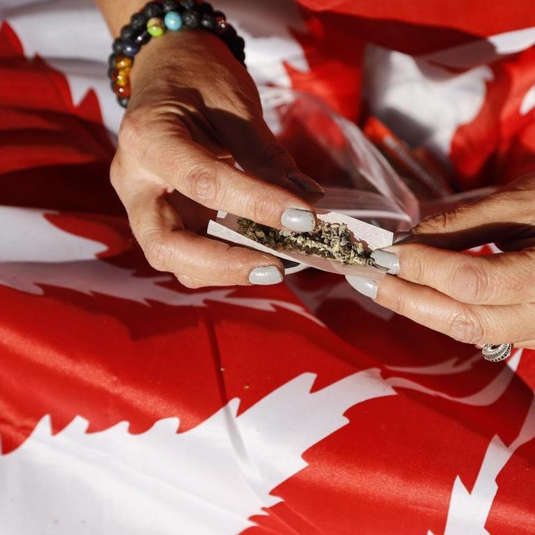 Jemand baut einen Joint auf einer kanadischen Flagge.