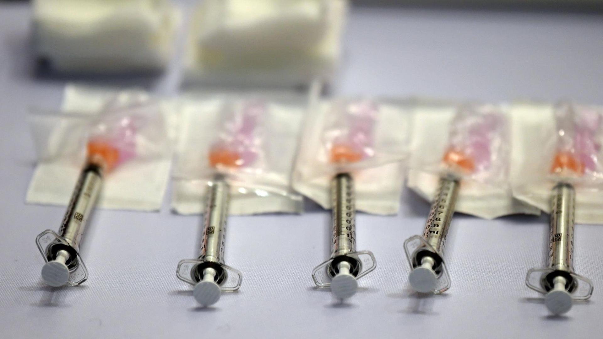 Fünf Spritzen liegen nebeneinander, die Nadeln in Dosen eines Corona-Impfstoffes, 2. April 2021, USA